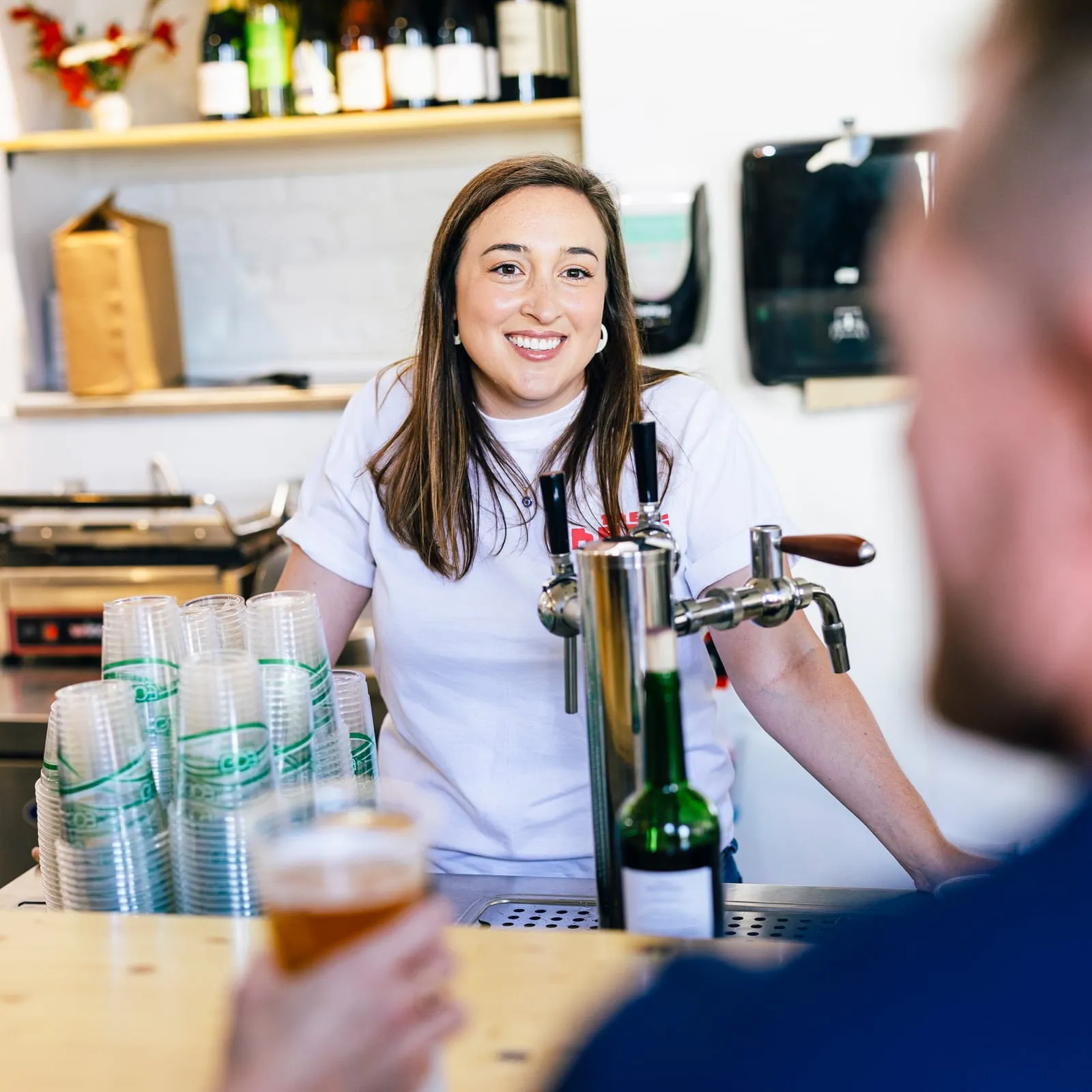 A staff member behind the taps while a customer waits with a beer