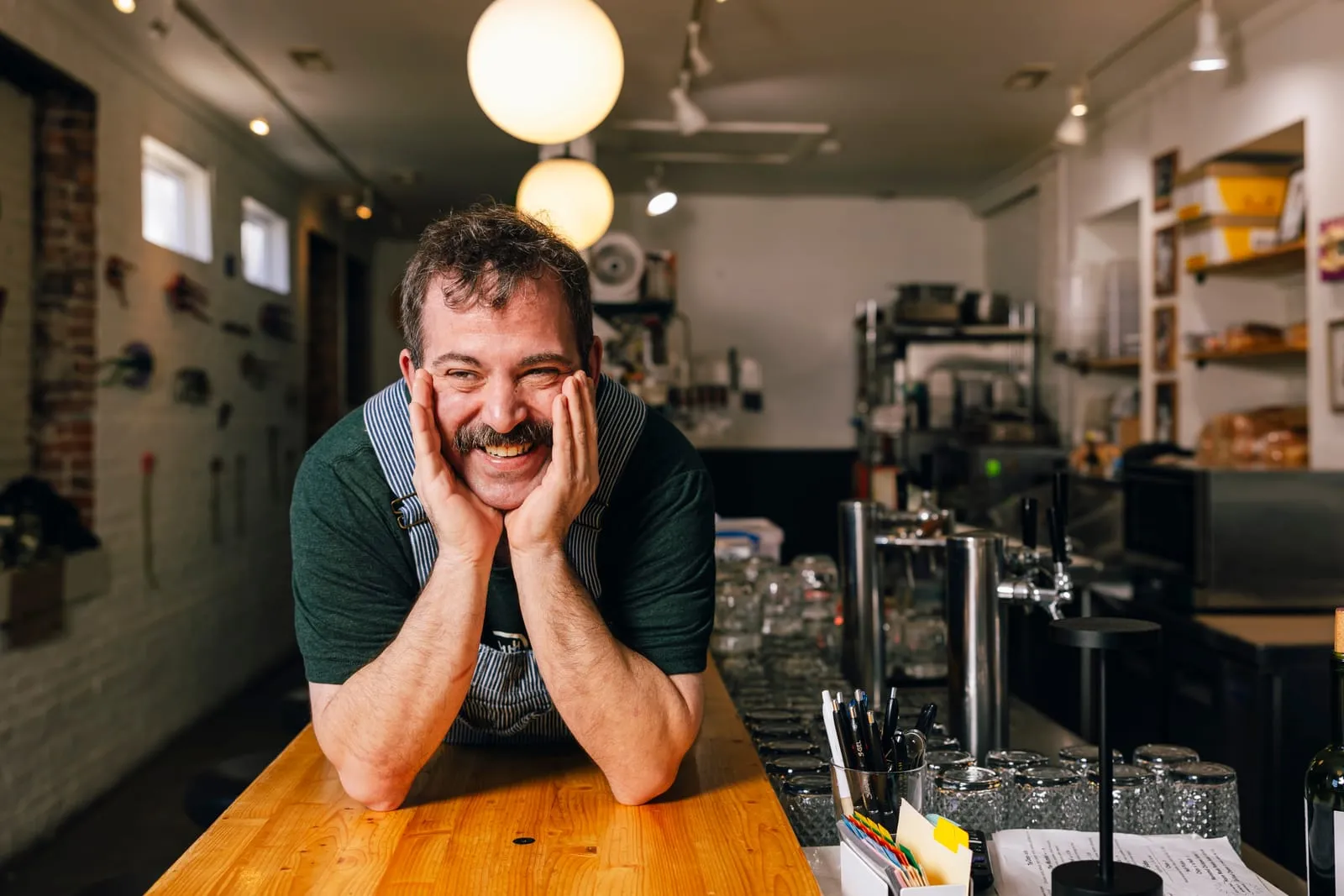 A smiling face resting on both hands at the end of the bar