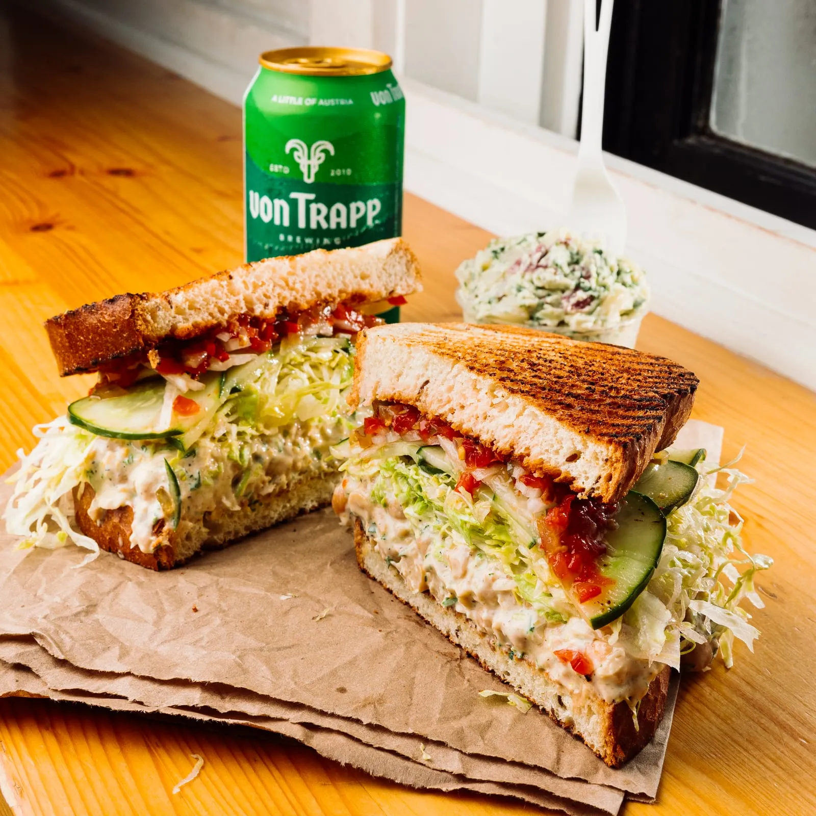 Grilled sandwich halves with slaw and a cold can