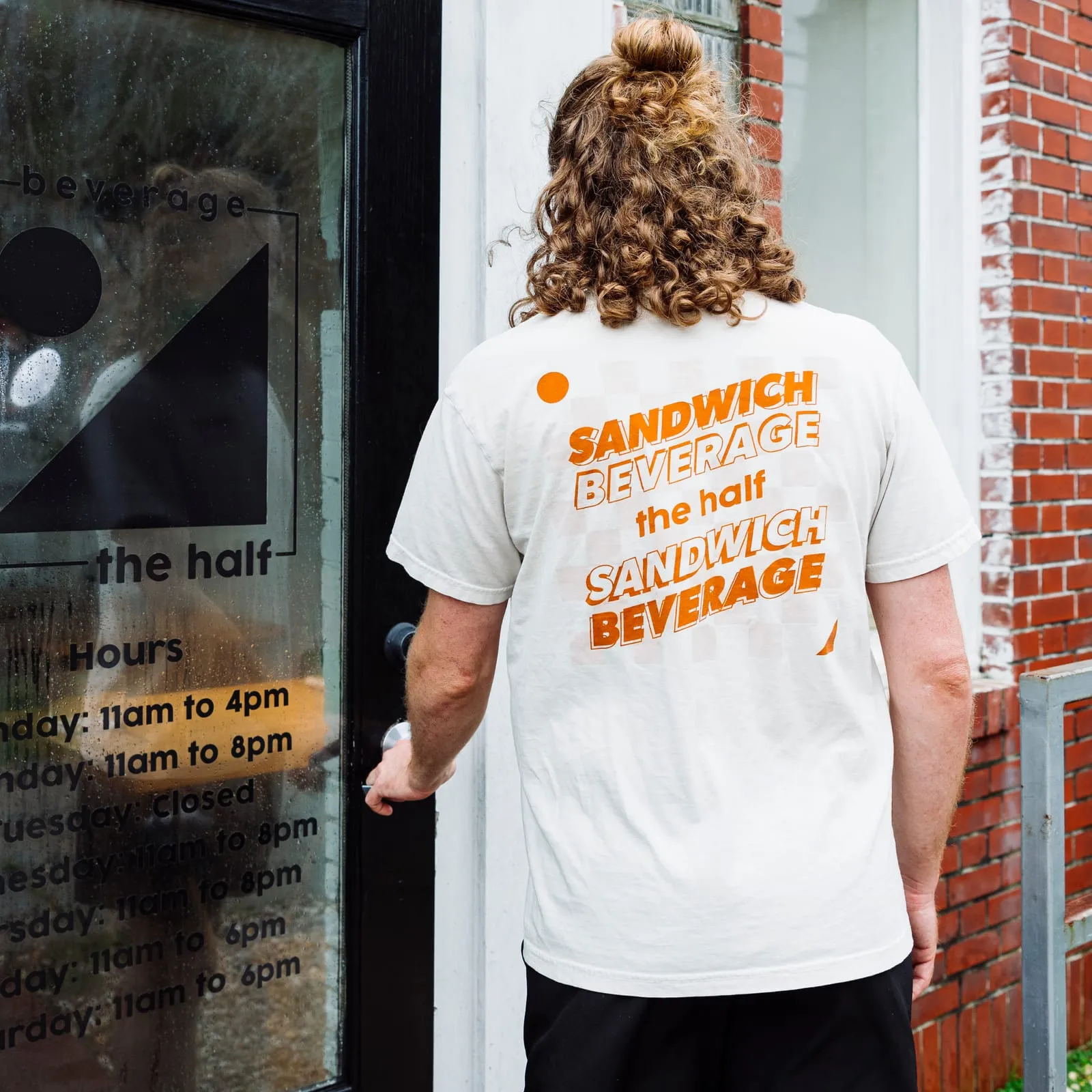 A staff member in a Sandwich Beverage tee at the front door