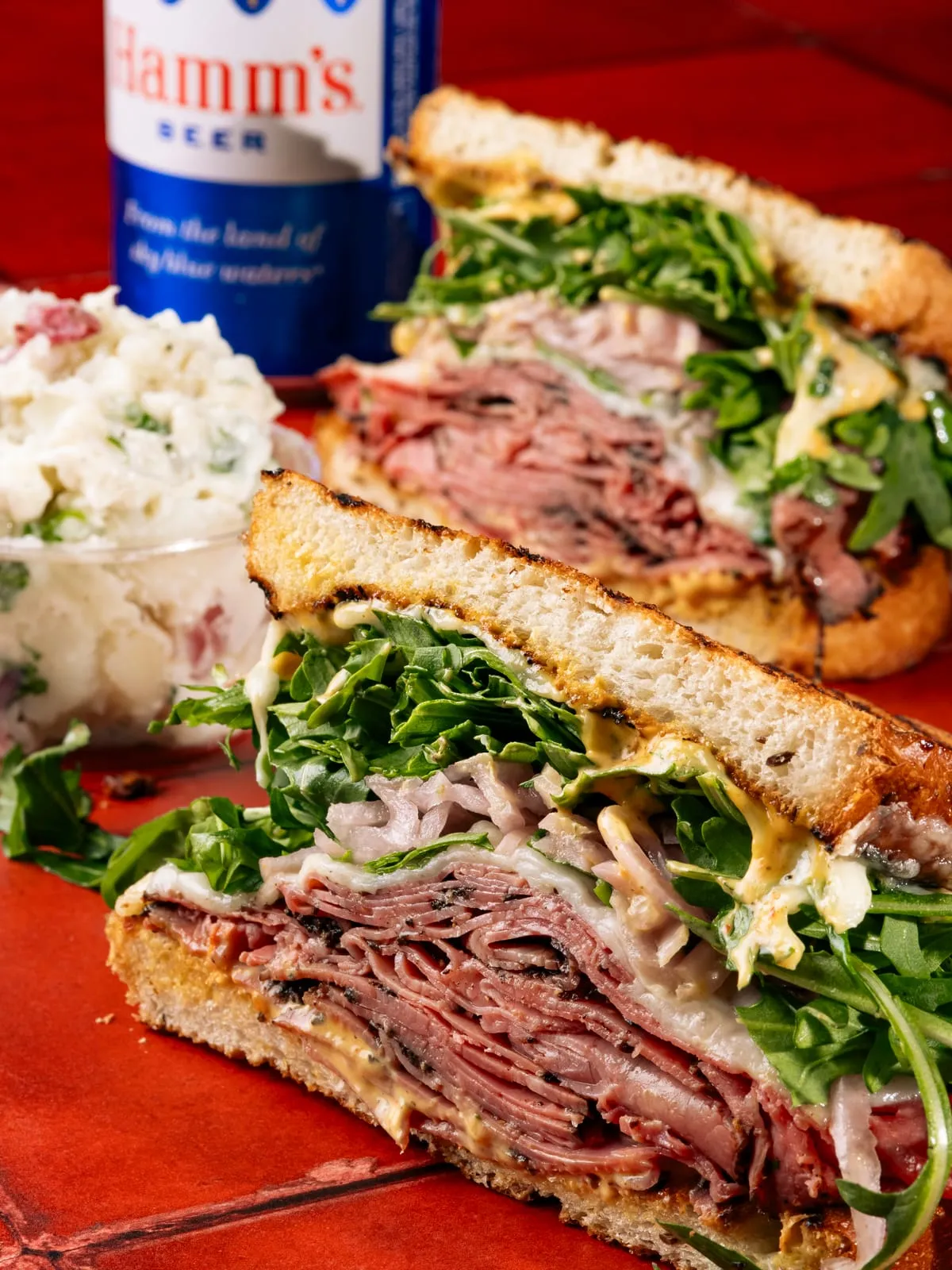 A pastrami and arugula sandwich with potato salad