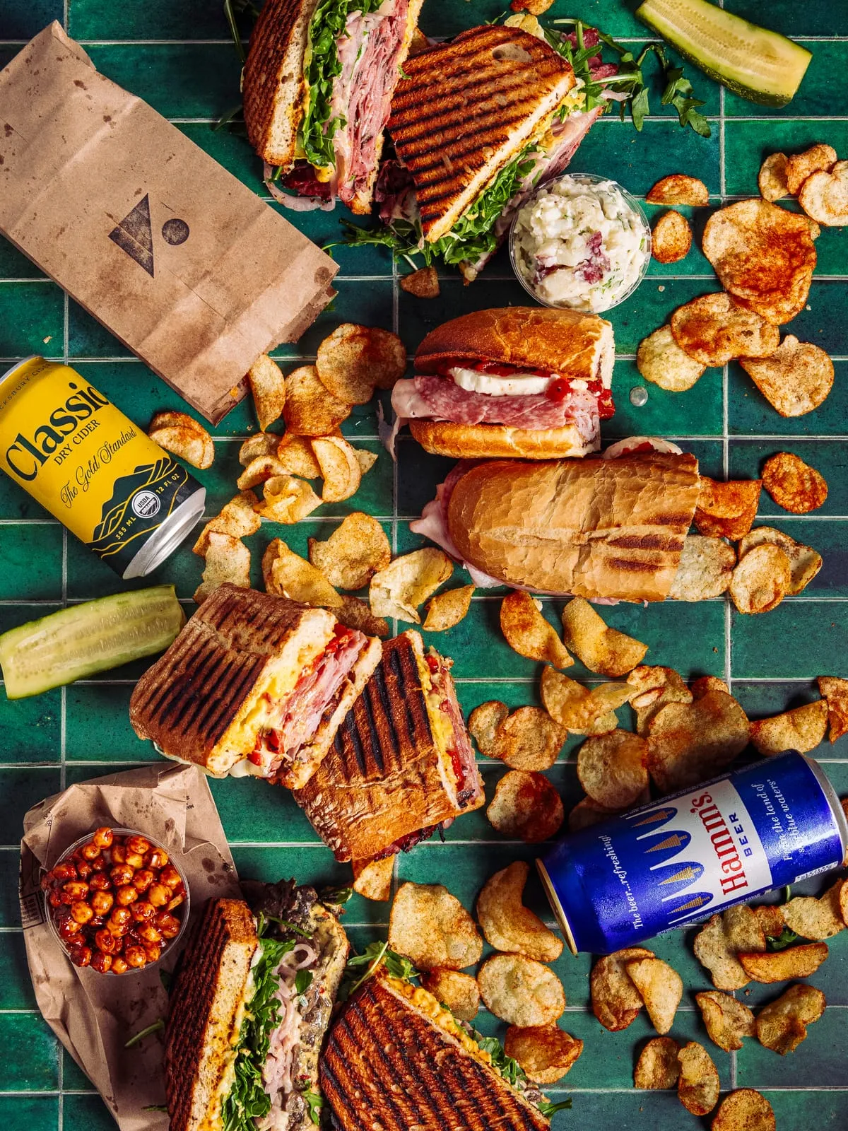 An overhead spread of sandwiches, chips and cans