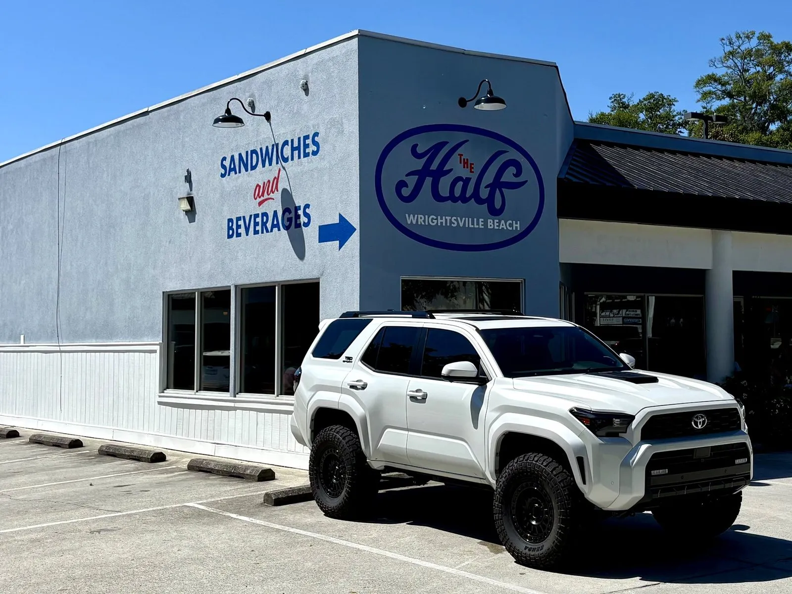 The blue Half building, SANDWICHES and BEVERAGES painted on the wall beside the Wrightsville Beach logo